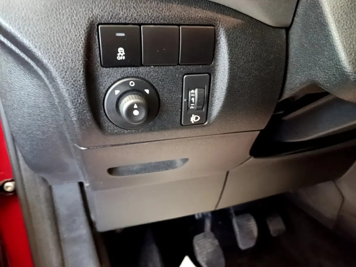 Détail du tableau de bord côté gauche du Citroën Berlingo rouge 2016 avec commandes d’éclairage et pédales visibles.