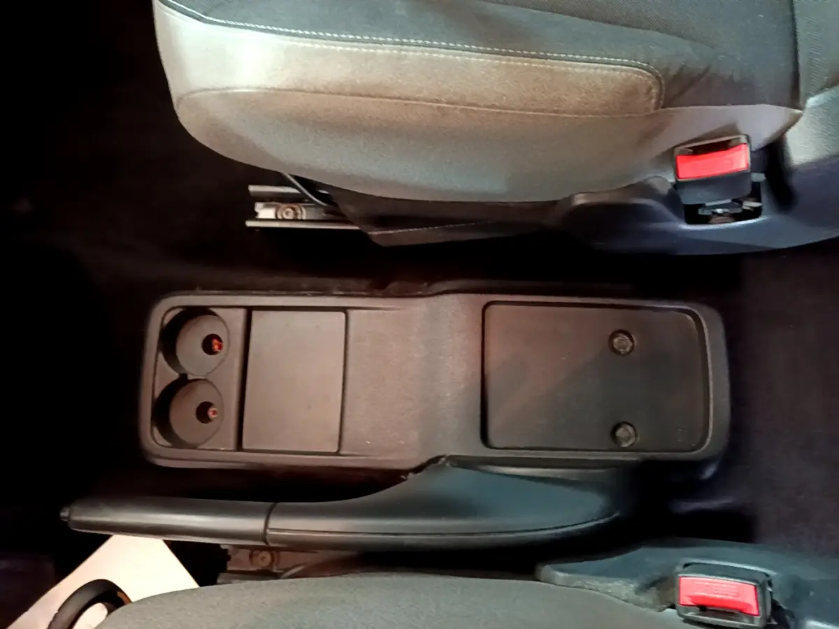 Vue rapprochée de la console centrale noire entre les sièges avant gris du Citroën Berlingo rouge 2016.