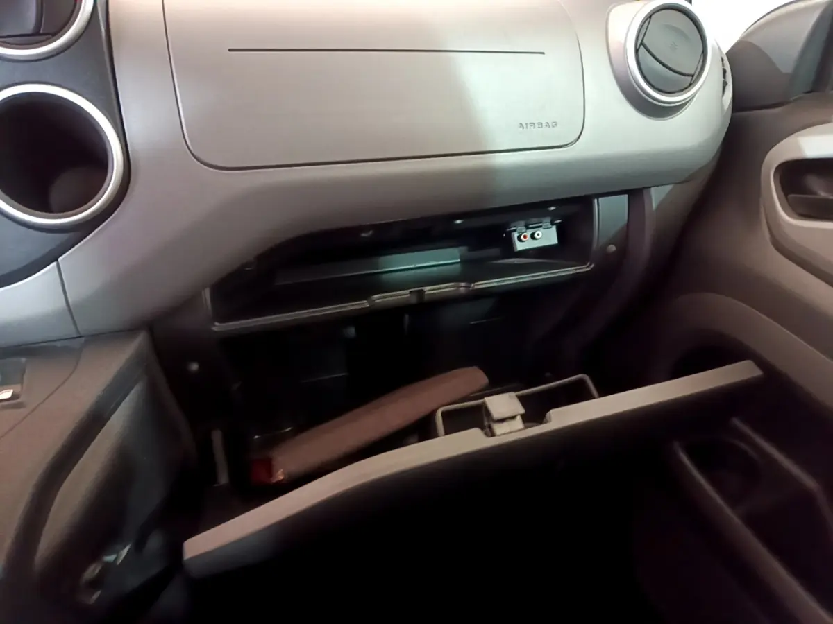 Intérieur du Citroën Berlingo 2016, vue sur la boîte à gants ouverte côté passager avec détails du tableau de bord gris.