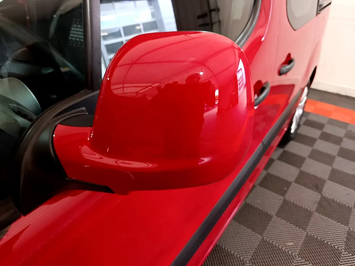 Rétroviseur côté gauche rouge brillant du Citroën Berlingo 2016, avec reflet de l'intérieur et partie de la porte visible.