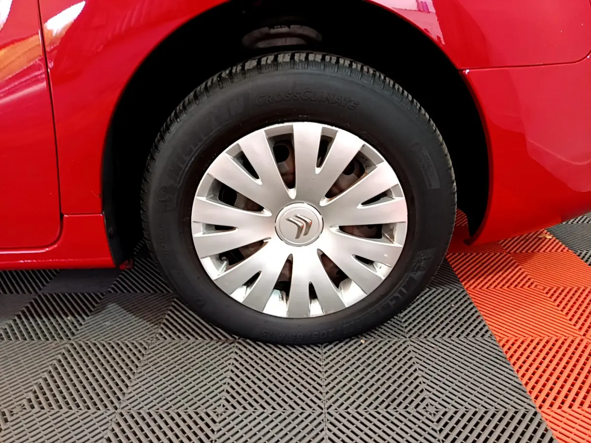 Gros plan sur la roue avant gauche d’un Citroën Berlingo rouge de 2016 avec enjoliveur argenté et pneu Michelin.