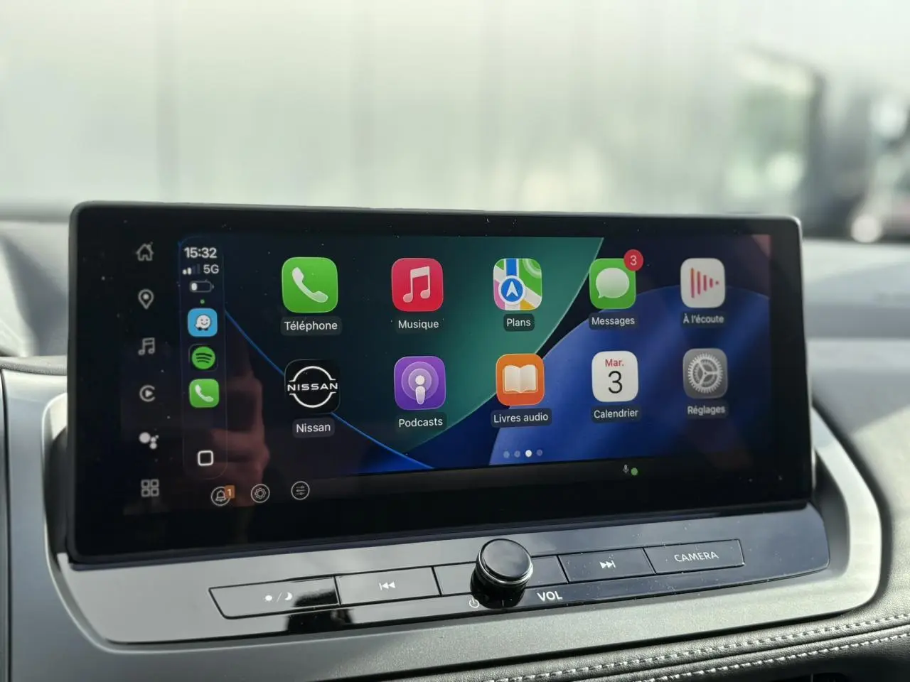 Écran tactile central du Nissan Qashqai blanc nacré 2025 affichant Apple CarPlay avec icônes colorées.