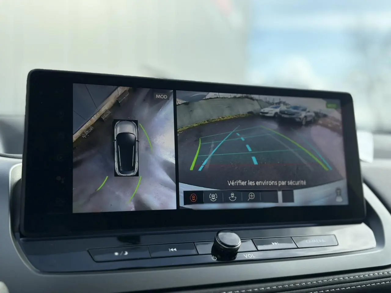 Écran intérieur du Nissan Qashqai blanc nacré montrant la caméra 360° et la vue arrière avec aides au stationnement.
