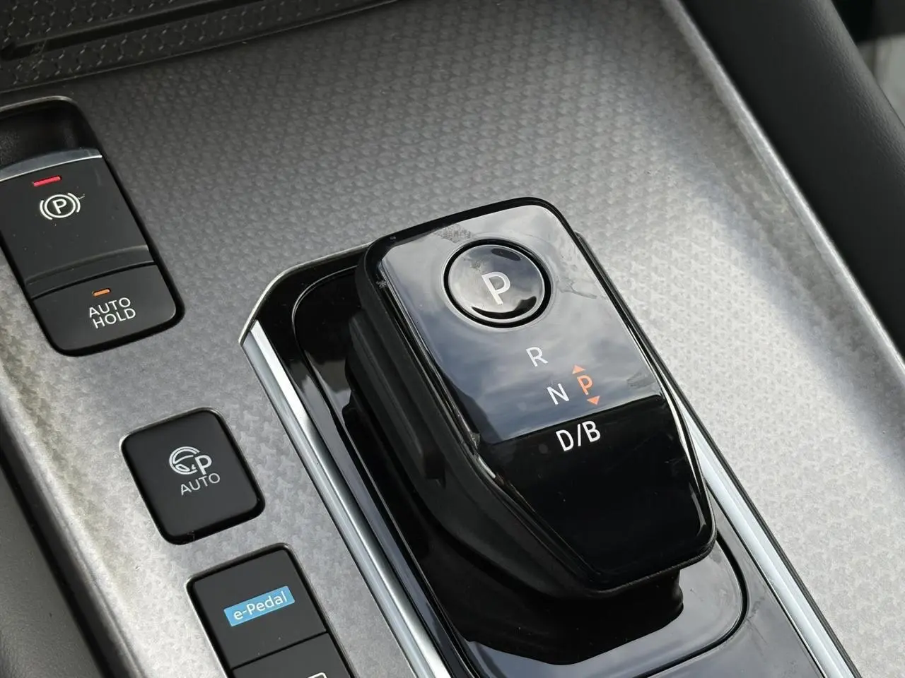 Gros plan sur la commande de boîte automatique noire et les boutons e-Pedal et frein à main dans un Nissan Qashqai blanc nacré.