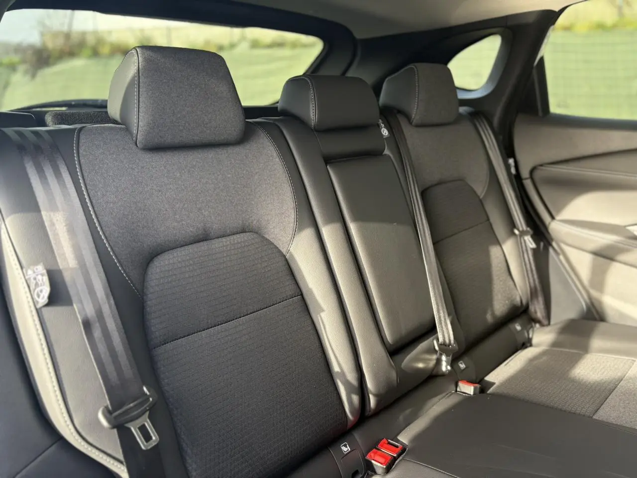 Vue intérieure des sièges arrière noirs du Nissan Qashqai III e-Power 2025 avec ceintures et appuie-têtes visibles.