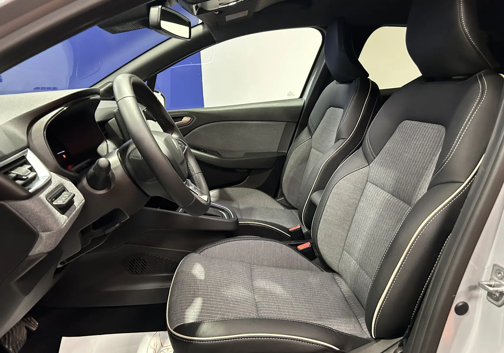 Vue intérieure côté conducteur de la Renault Clio V E-Tech 145ch avec sièges bi-matière gris et noir.