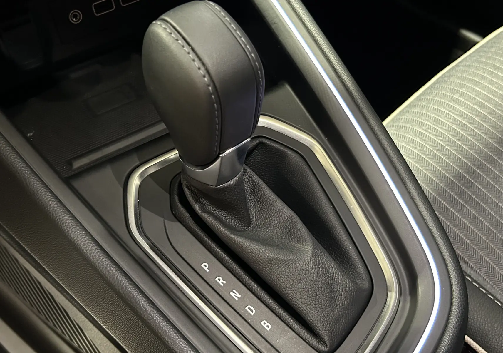 Gros plan sur le levier de vitesses automatique noir de la Renault Clio V E-Tech, intérieur avec coutures apparentes.