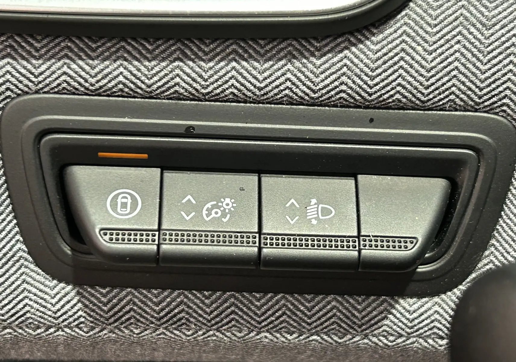 Boutons de réglage des feux et verrouillage sur tableau de bord avec tissu gris à motif chevrons dans Renault Clio V E-Tech.