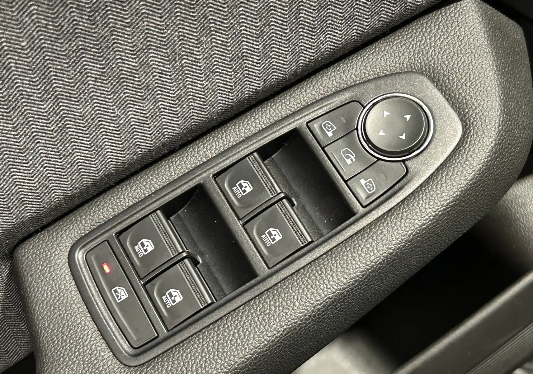 Gros plan sur les commandes de lève-vitres et réglage des rétroviseurs côté conducteur d’une Renault Clio V.