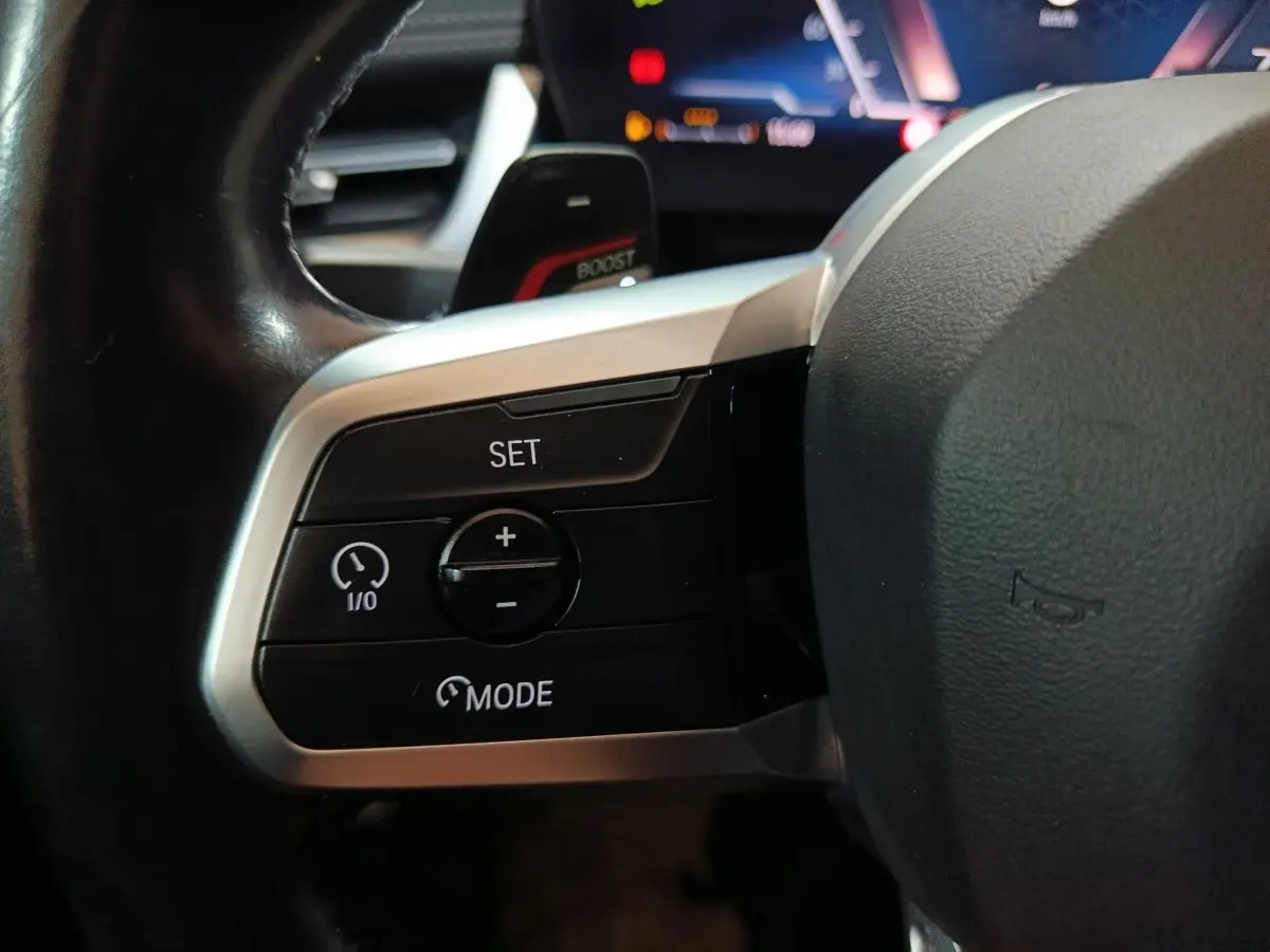 Gros plan sur les commandes de régulateur de vitesse au volant cuir noir du BMW X1 xDrive23i M Sport 2023.