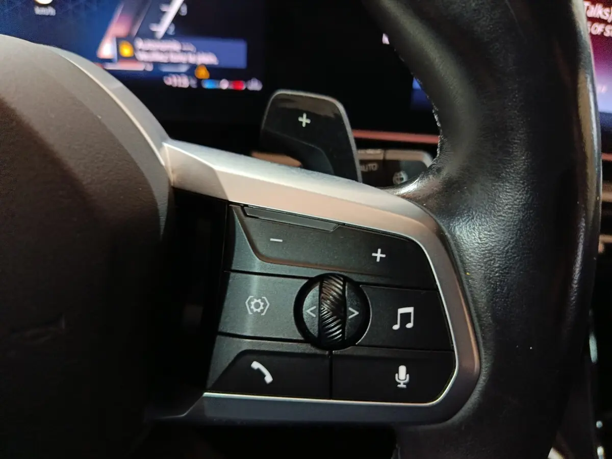 Gros plan sur les commandes multifonctions en cuir noir du volant du BMW X1 xDrive23i M Sport 2023.