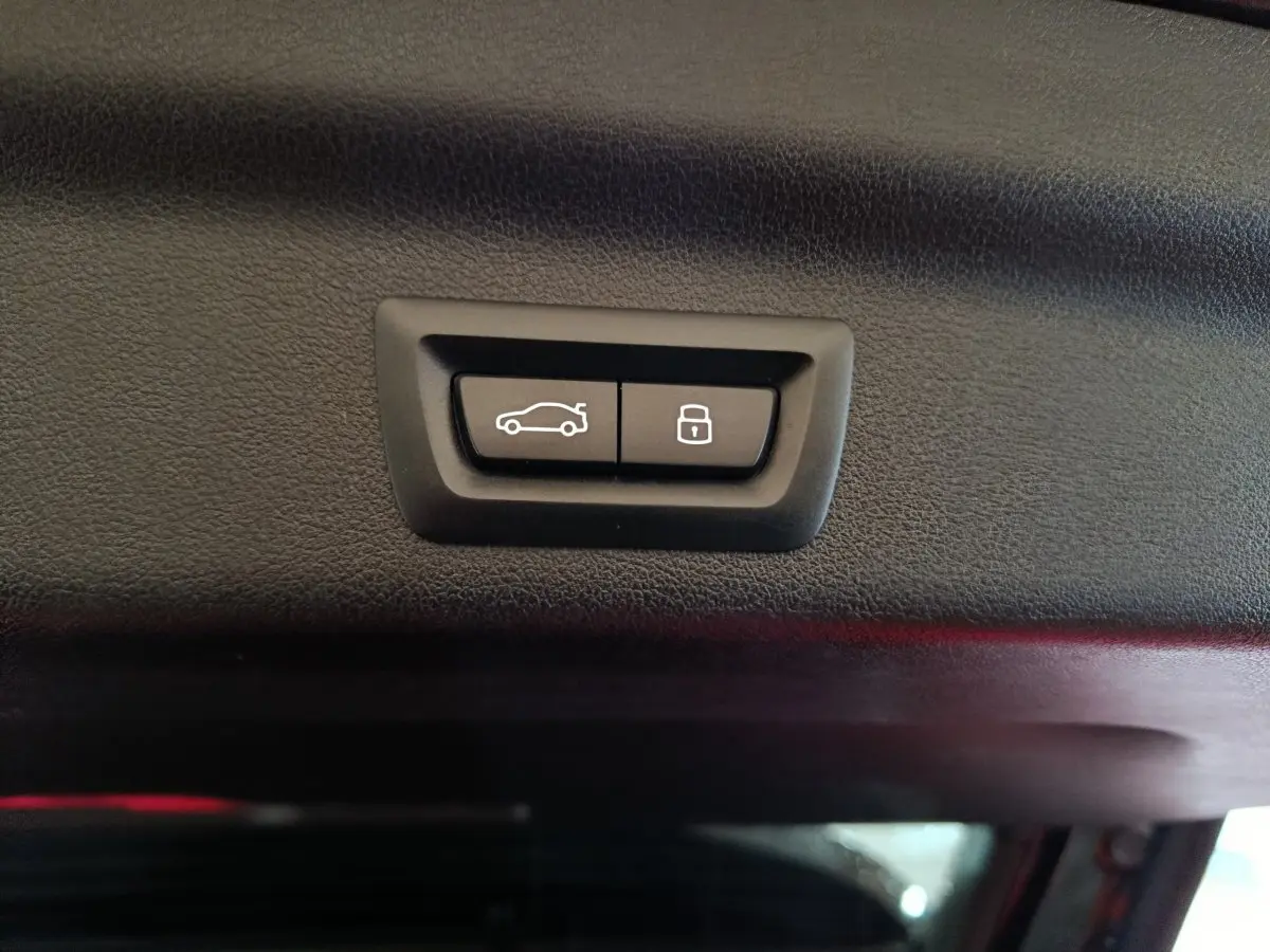 Gros plan sur les boutons d'ouverture et de verrouillage du coffre noir intérieur du BMW X1 xDrive23i M Sport 2023.