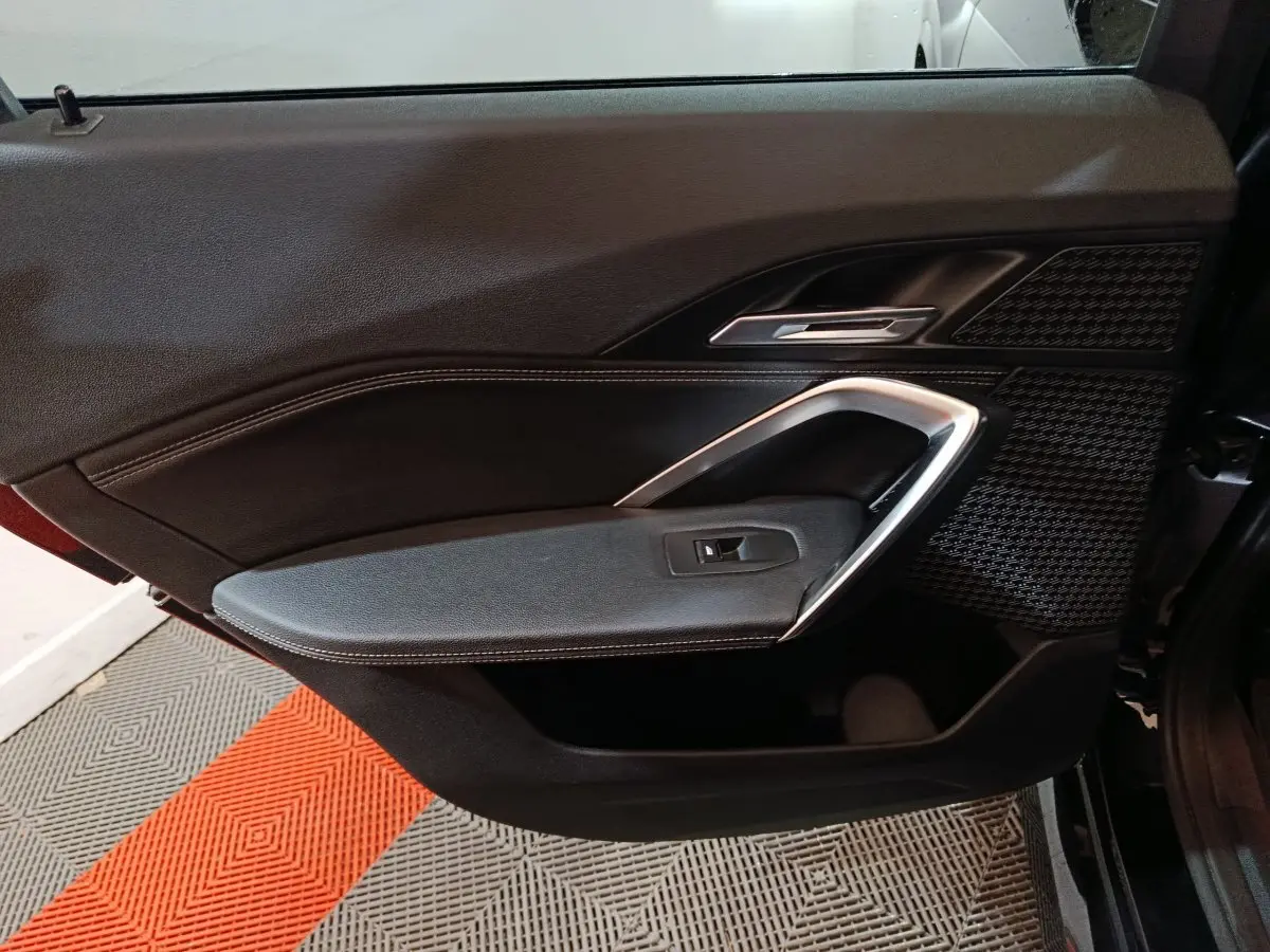 Vue intérieure côté gauche de la porte avant noire du BMW X1 xDrive23i M Sport avec insert argenté et tissu texturé.