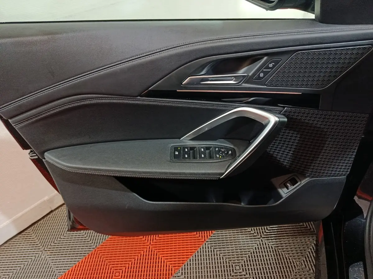 Vue rapprochée de la porte avant gauche noire du BMW X1 xDrive23i M Sport 2023 avec commandes de vitres et poignée alu.