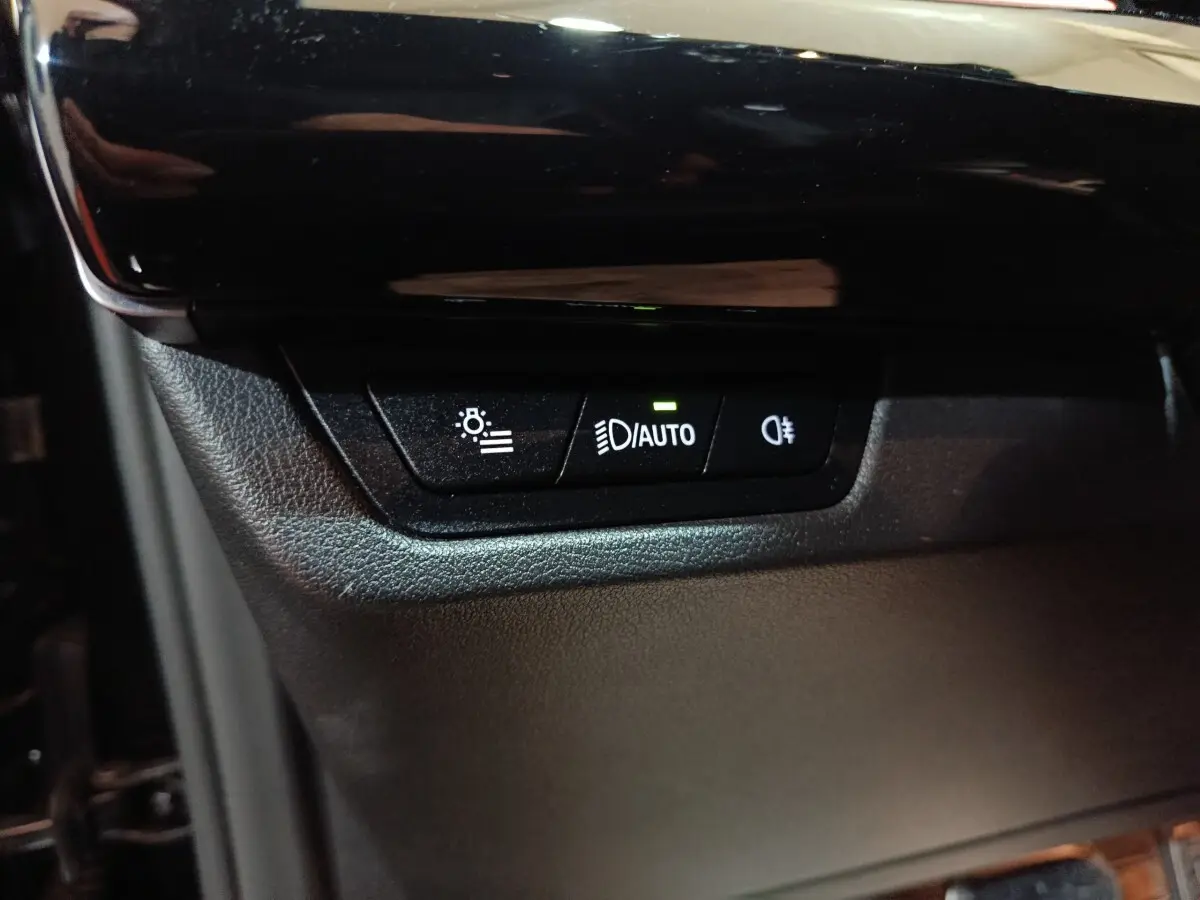 Gros plan sur les commandes d’éclairage automatiques dans l’habitacle noir du BMW X1 xDrive23i M Sport 2023.