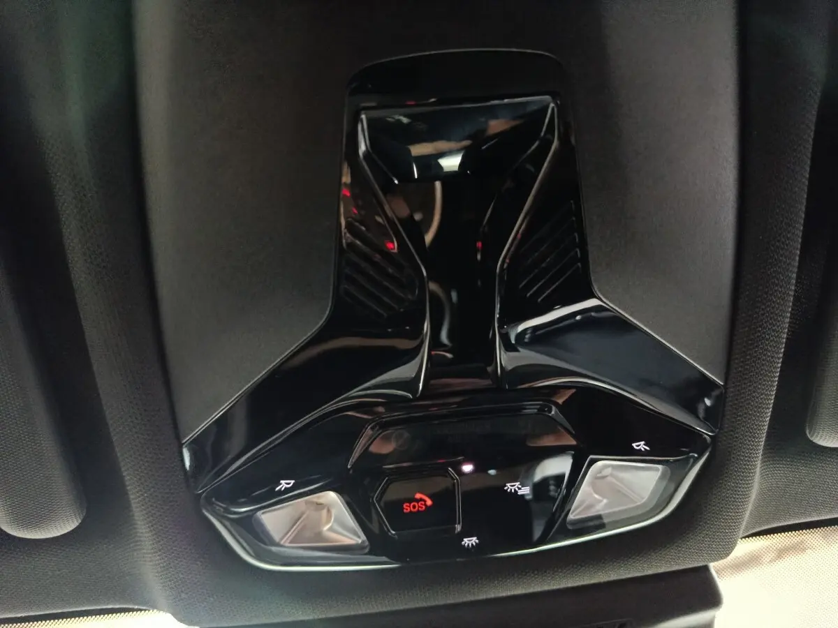 Vue en contre-plongée du plafonnier noir brillant avec bouton SOS rouge et éclairages intégrés dans un BMW X1 2023.