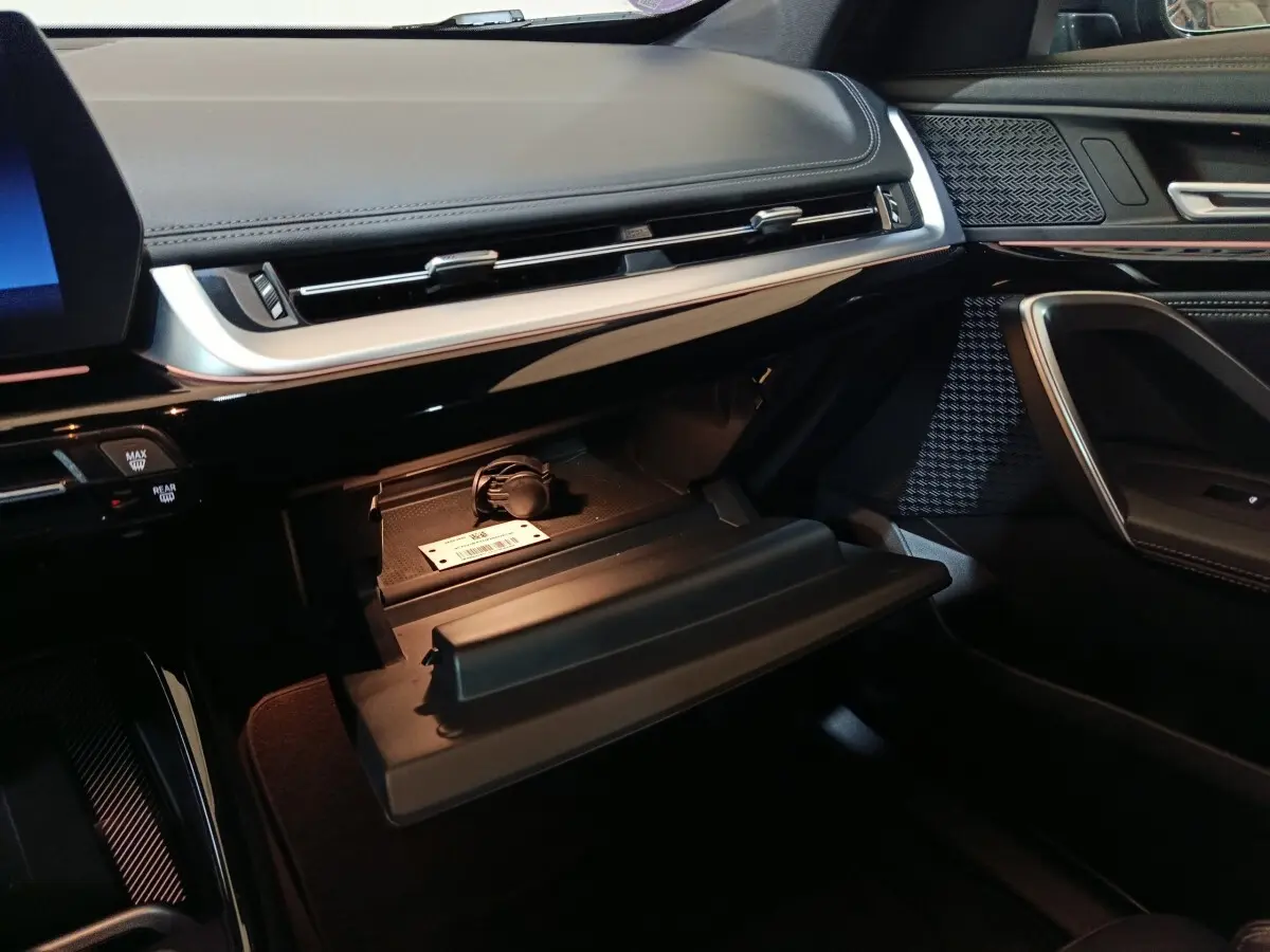 Vue intérieure côté passager du tableau de bord noir et boîte à gants ouverte du BMW X1 xDrive23i M Sport 2023.