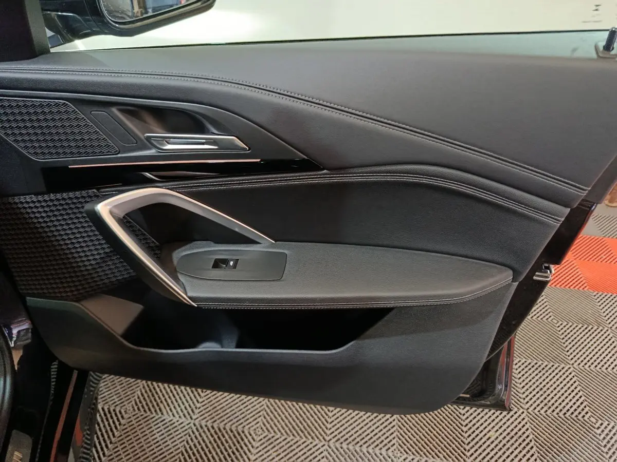 Vue rapprochée de la porte intérieure côté gauche noire du BMW X1 xDrive23i M Sport 2023 avec détails chromés et tissu texturé.