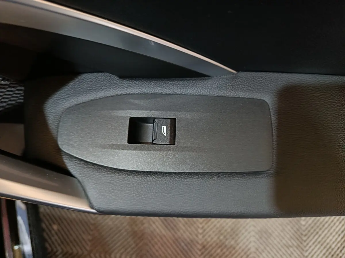 Gros plan sur le bouton de commande de la vitre électrique, sur la porte intérieure noire d’une BMW X1 2023.