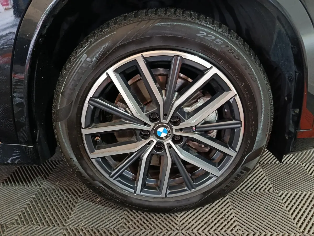 Gros plan sur la roue avant droite noire d’un BMW X1 xDrive23i M Sport 2023 avec jante alliage bicolore.