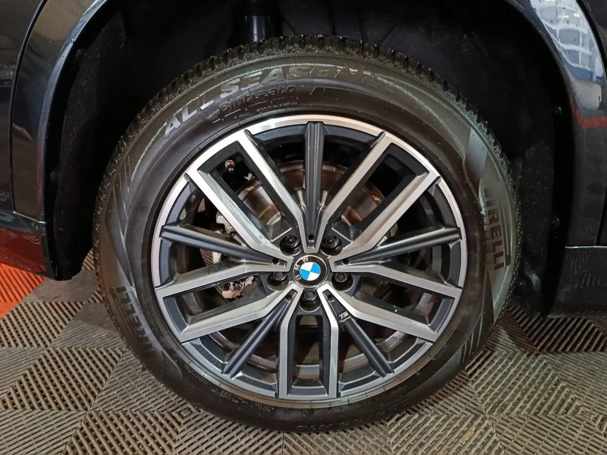 Gros plan sur la jante alliage noire et argentée avec logo BMW, montée sur pneu Pirelli All Season du BMW X1 noir.