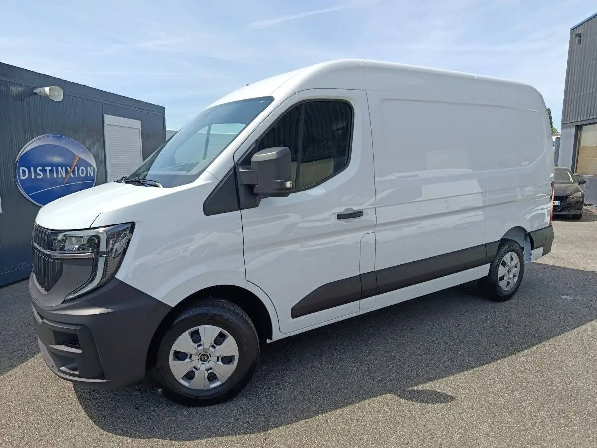 Renault Master blanc en vue 3/4 avant droit, avec pare-chocs et bas de caisse noirs, stationné devant un bâtiment.