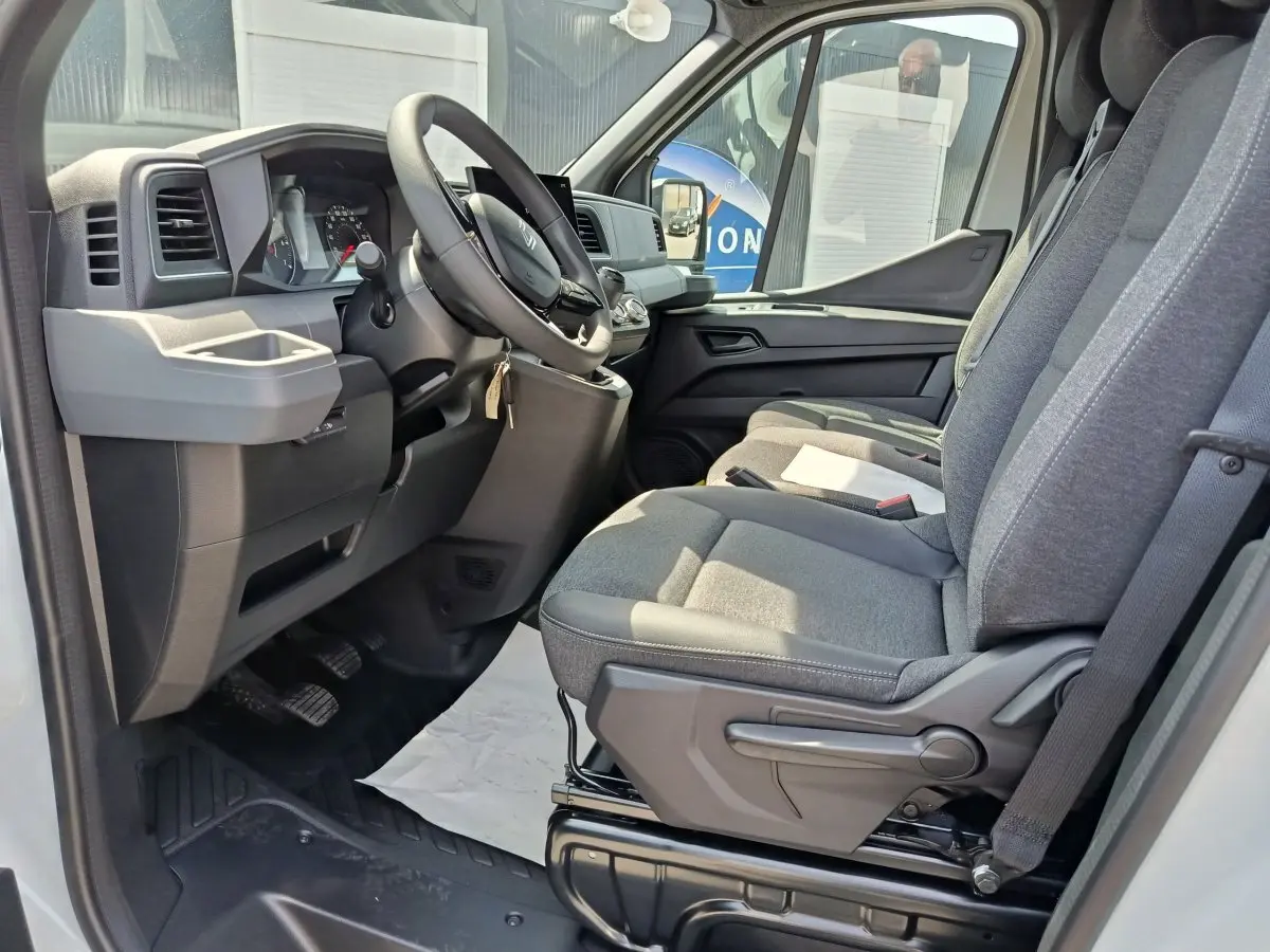 Intérieur côté conducteur du Renault Master blanc 2025, montrant le tableau de bord et les sièges gris en tissu.