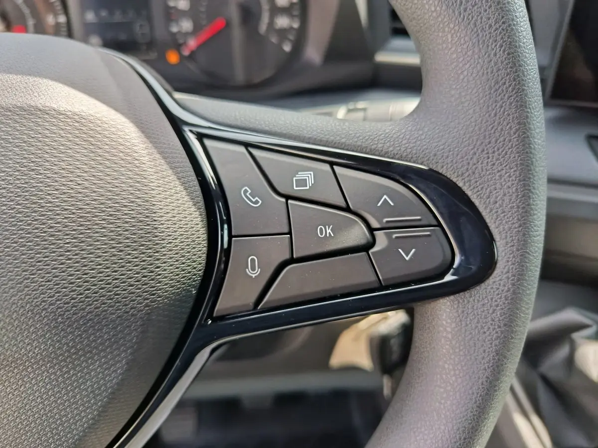 Gros plan sur les commandes multifonctions noires du volant du Renault Master blanc, avec tableau de bord en arrière-plan.