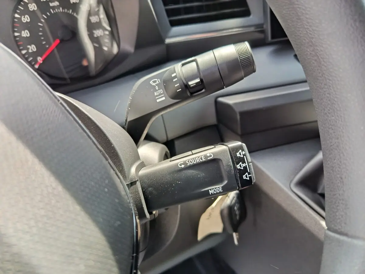 Gros plan sur les commandes au volant du Renault Master blanc, montrant les boutons source et mode sur la manette.
