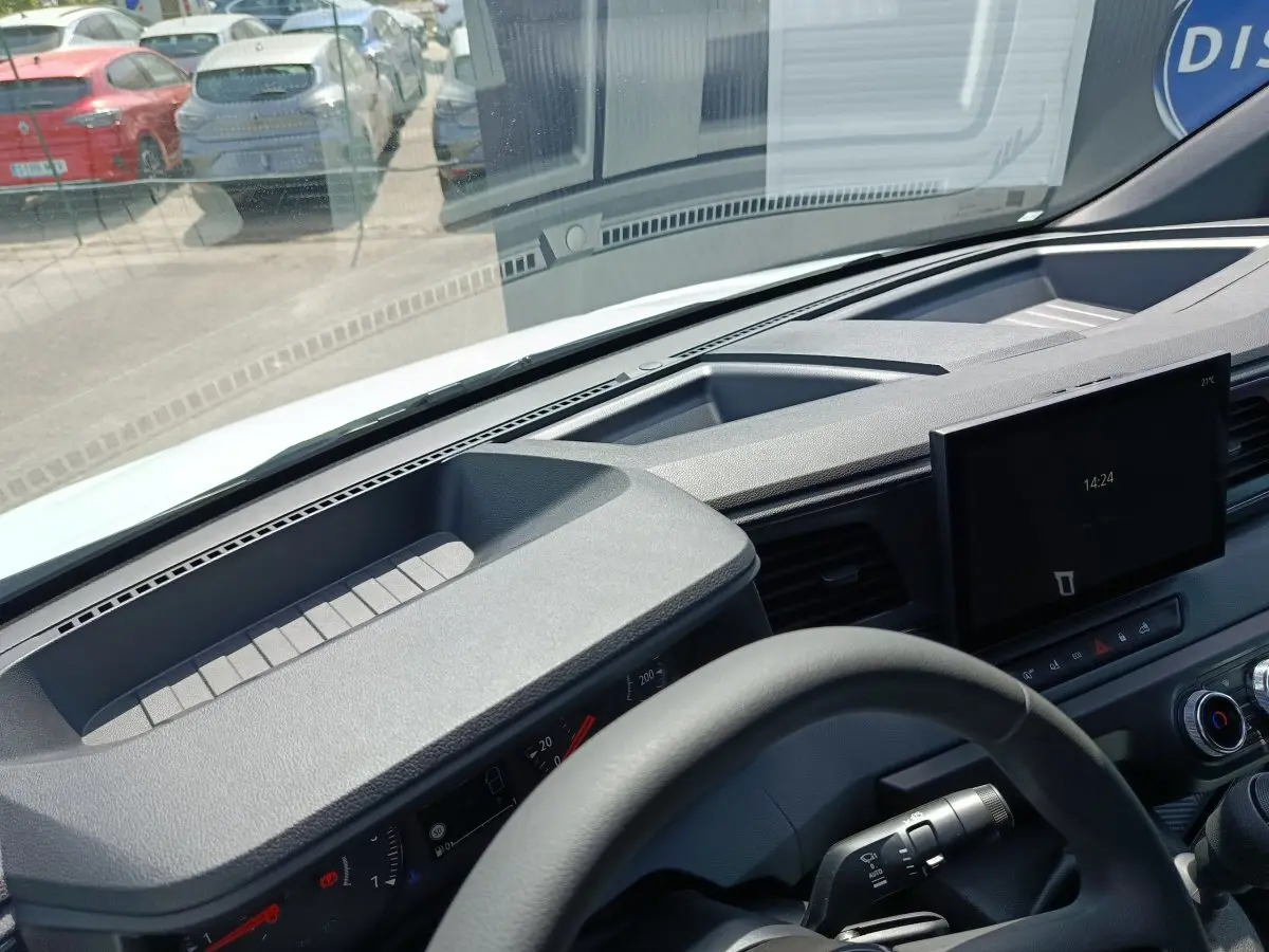 Vue intérieure du tableau de bord et volant du Renault Master blanc, avec écran tactile central et commandes visibles.
