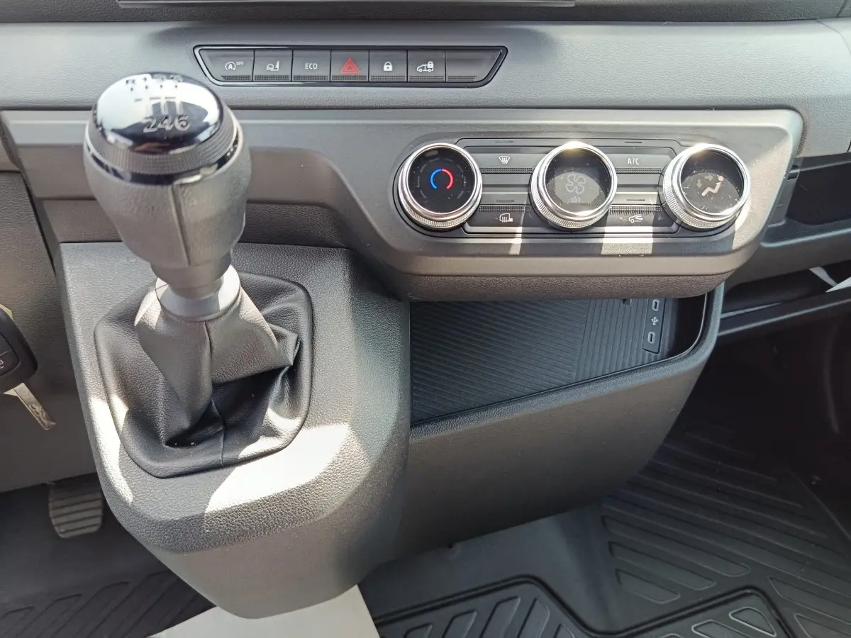 Gros plan intérieur sur la console centrale du Renault Master blanc 2025, avec levier de vitesses manuel et commandes climatisation.