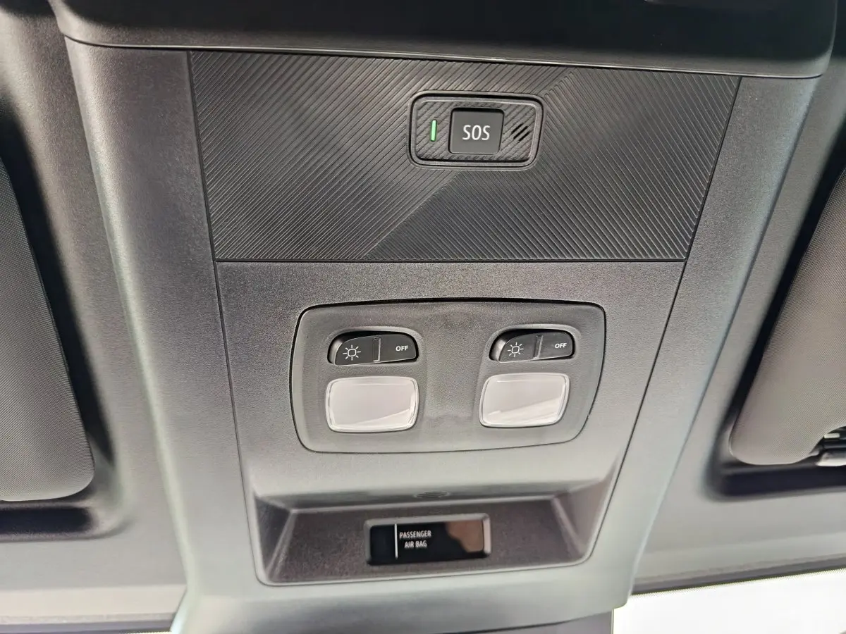 Vue en contre-plongée du plafonnier gris avec bouton SOS et commandes d’éclairage du Renault Master blanc 2025.