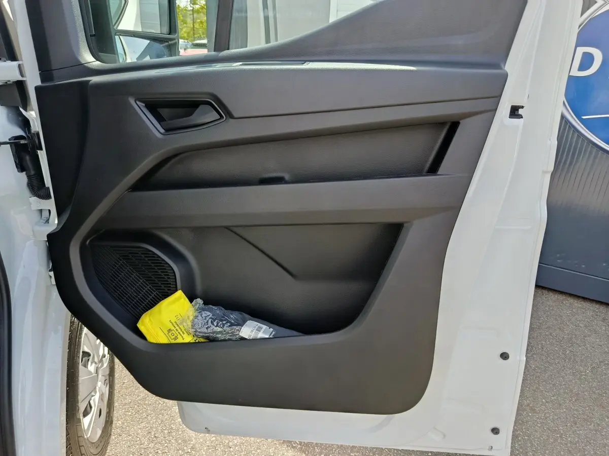 Vue rapprochée de la porte avant gauche noire du Renault Master blanc avec rangement contenant un objet jaune.