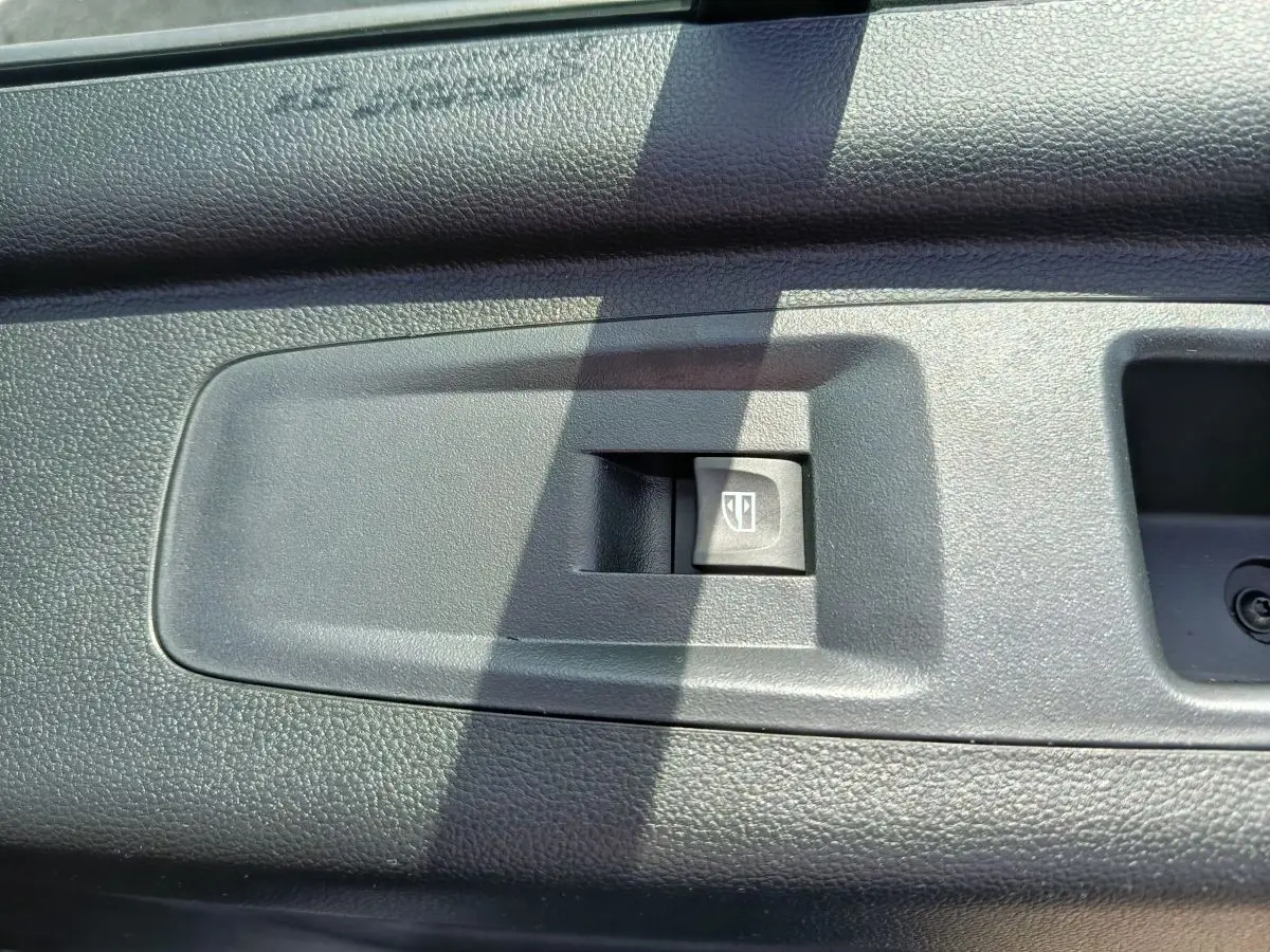 Bouton de commande de lève-vitre électrique sur la porte intérieure noire du Renault Master FG L2H2 blanc, vue rapprochée.