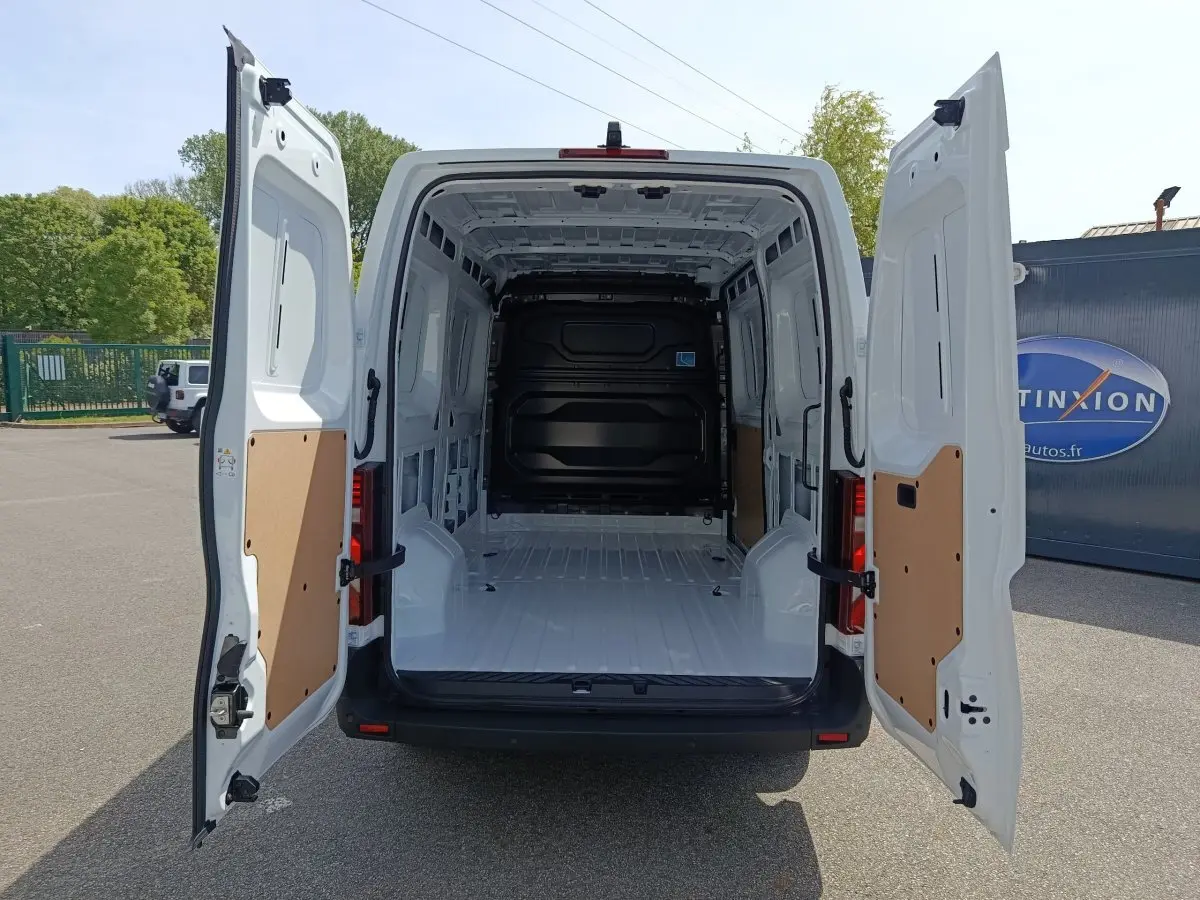 Vue arrière du Renault Master blanc 2025 avec portes arrière ouvertes montrant l'espace de chargement vide et cloison pleine noire.