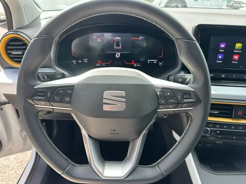 Vue rapprochée du volant cuir multifonction noir avec surpiqûres blanches du SEAT Arona 2025, tableau de bord numérique visible.
