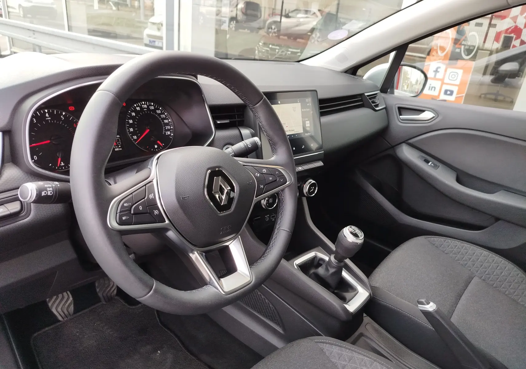 Vue intérieure côté conducteur de la Renault Clio V Business 2020, volant cuir, tableau de bord moderne et levier de vitesses manuel.