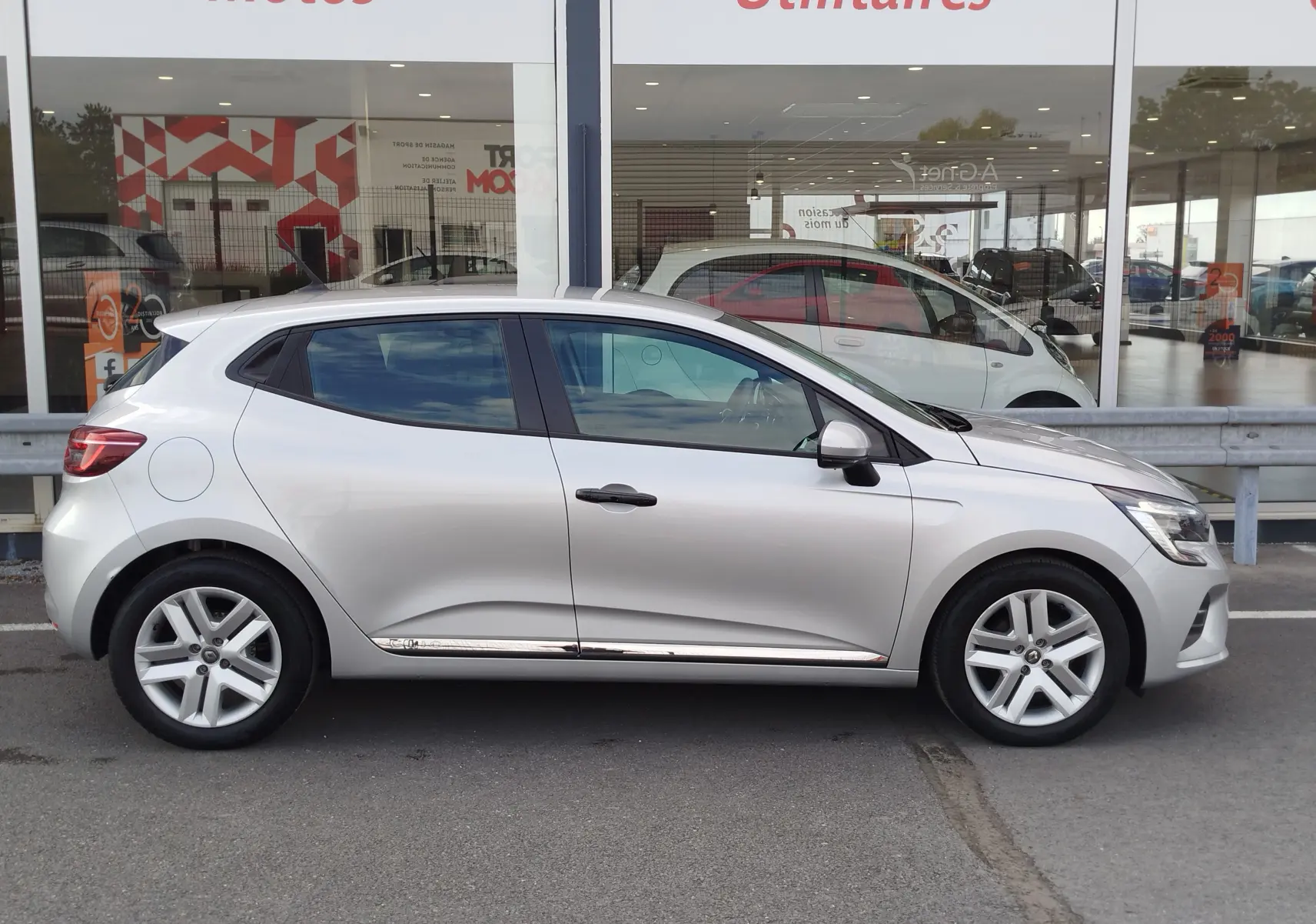 Profil côté gauche d'une Renault Clio V Business gris platine, avec jantes alliage et lignes épurées visibles.