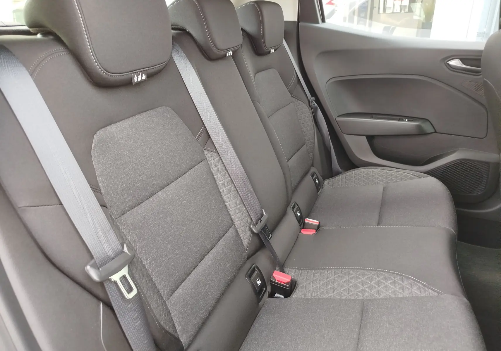 Vue intérieure côté droit des sièges arrière gris foncé de la Renault Clio V Business 2020 avec ceintures de sécurité visibles.