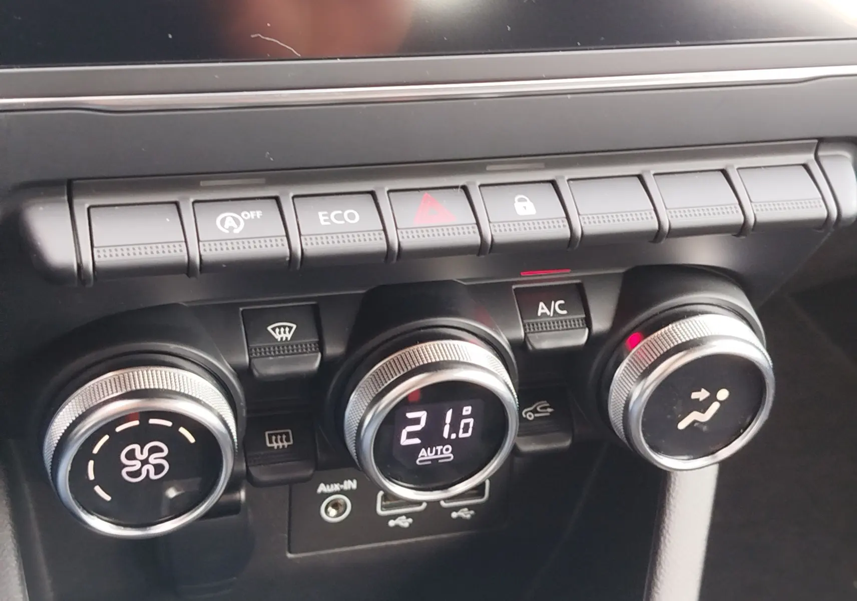 Gros plan sur la console centrale de la Renault Clio V Business, montrant les commandes de climatisation et les boutons fonctionnels.