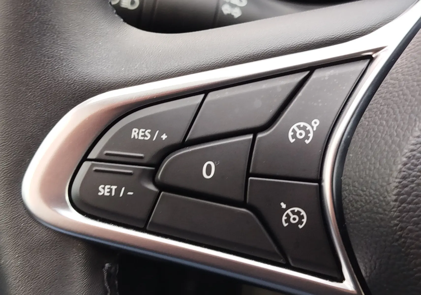 Gros plan sur les commandes de régulateur de vitesse au volant de la Renault Clio V Business gris platine, intérieur noir.