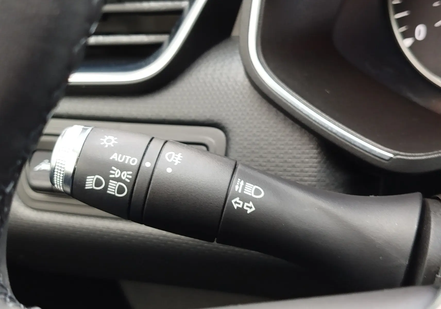 Gros plan sur la manette de commande des phares et clignotants du tableau de bord intérieur d'une Renault Clio V gris platine.