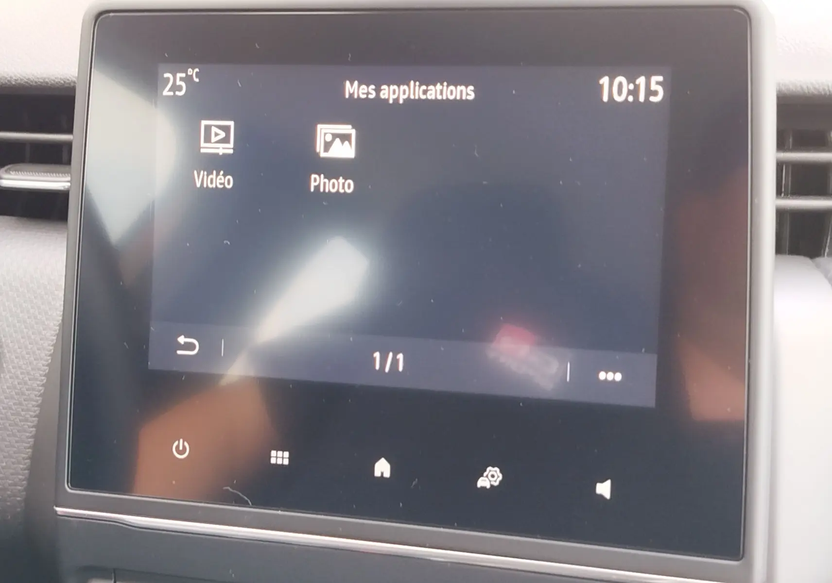 Écran tactile central de la Renault Clio V Business 2020 affichant les applications vidéo et photo, ambiance intérieure grise.