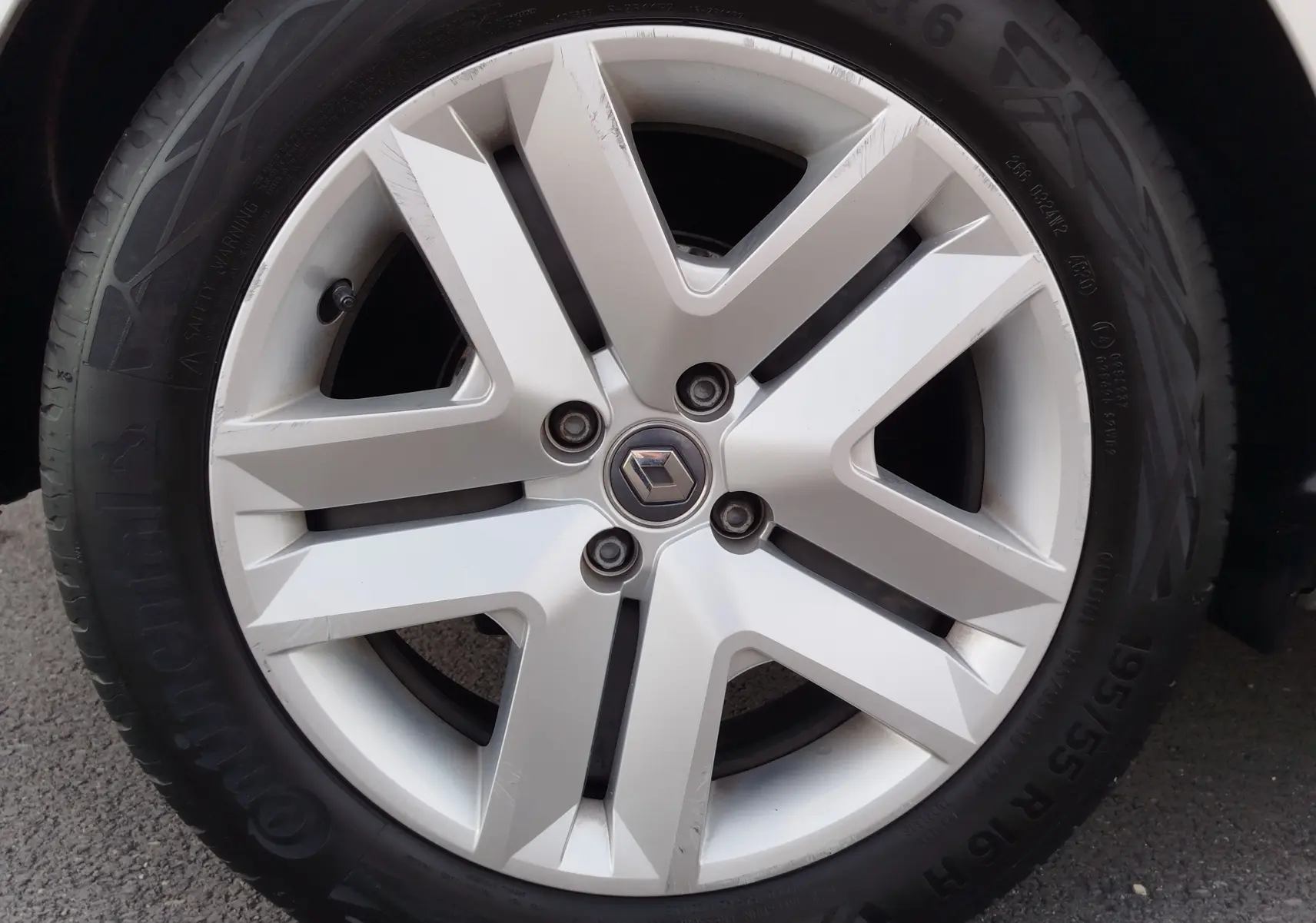 Gros plan sur la jante alliage argentée avec logo Renault au centre, montée sur pneu Continental d'une Clio V gris platine.