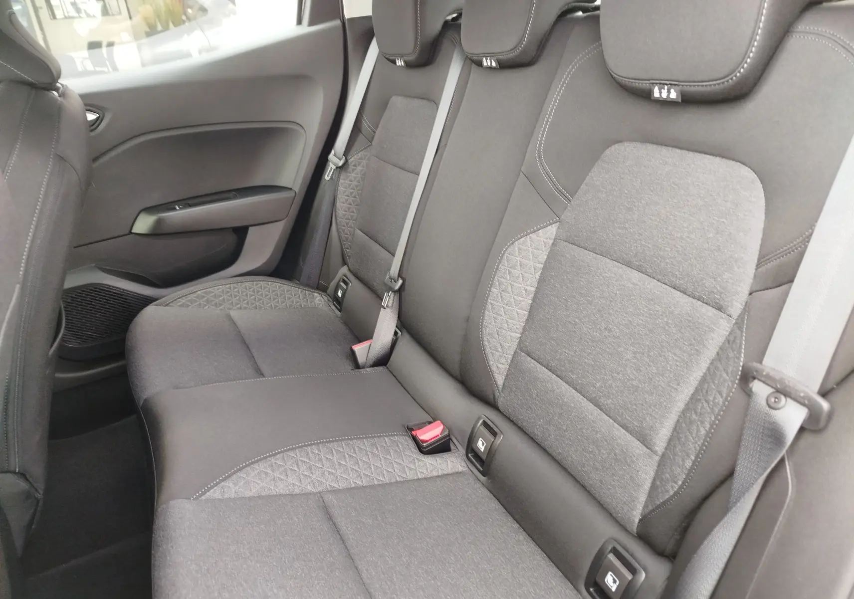 Vue latérale intérieure sur les sièges arrière gris foncé avec surpiqûres et ceintures de sécurité visibles d'une Renault Clio V.