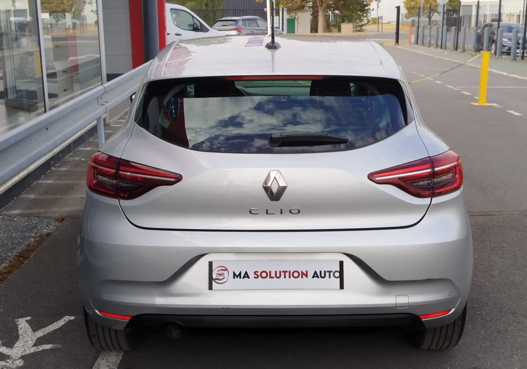 Vue arrière d'une Renault Clio V Business gris platine, avec feux arrière LED et logo Renault bien visibles.