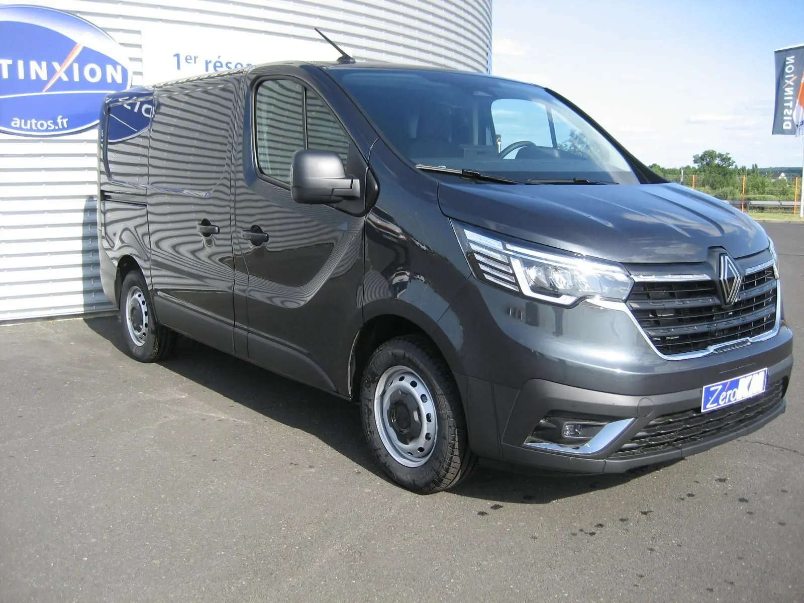 Renault Trafic Fourgon gris comète vu en 3/4 avant droit, avec calandre chromée et jantes acier simples.