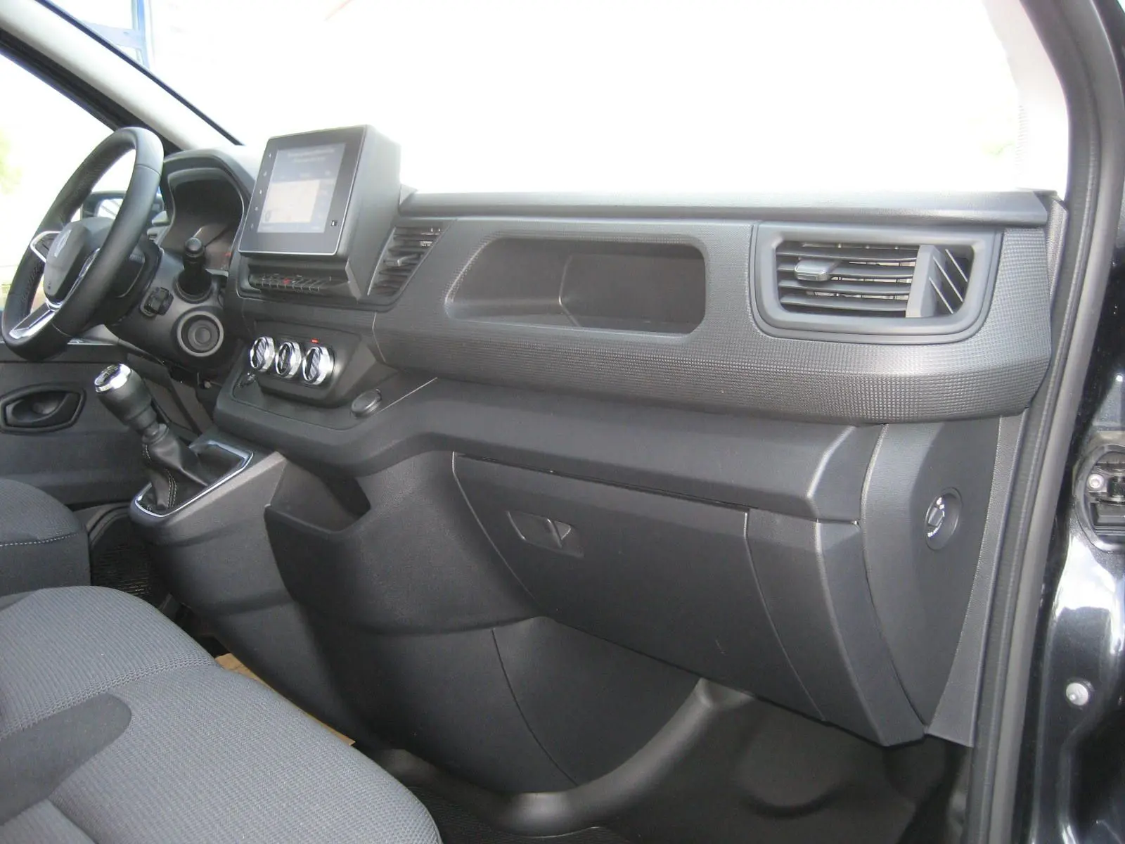 Intérieur côté passager du Renault Trafic Fourgon gris comète 2025, tableau de bord avec écran tactile et commandes manuelles.