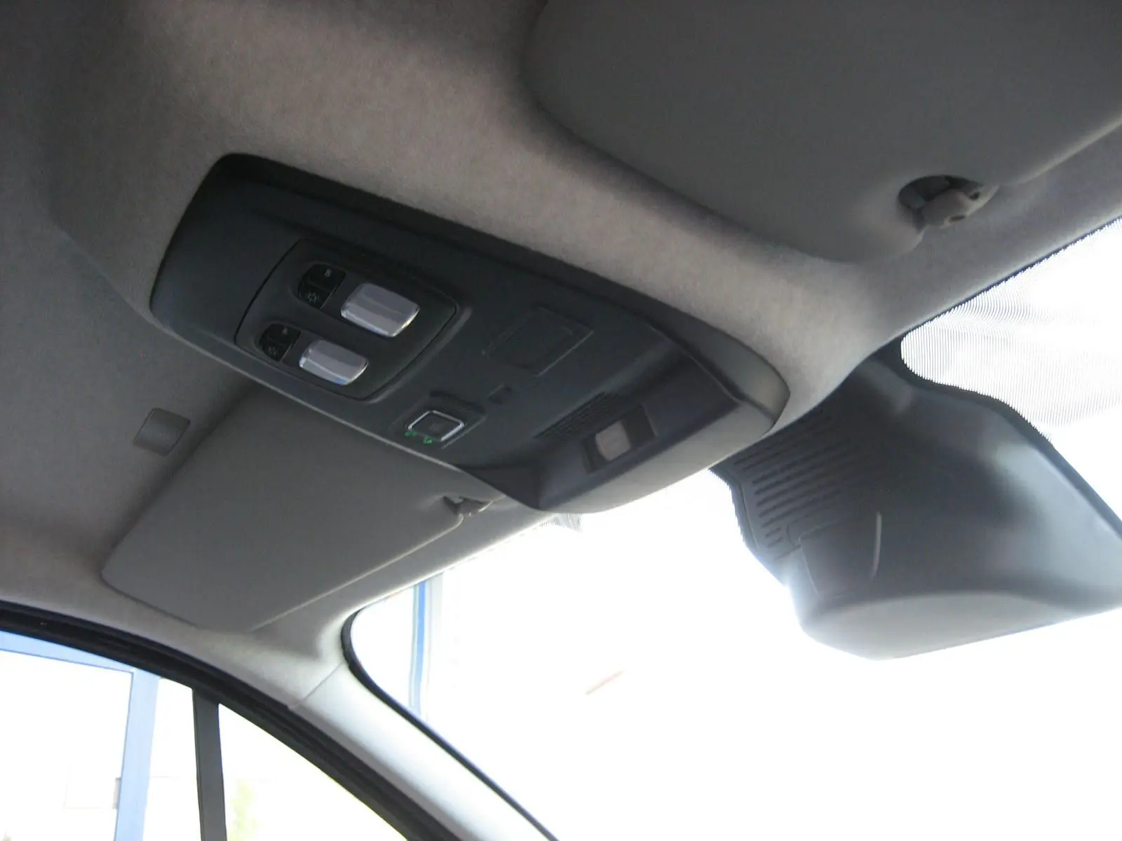 Vue intérieure du plafond avant du Renault Trafic Fourgon gris comète, avec commandes d'éclairage et pare-soleil côté conducteur.