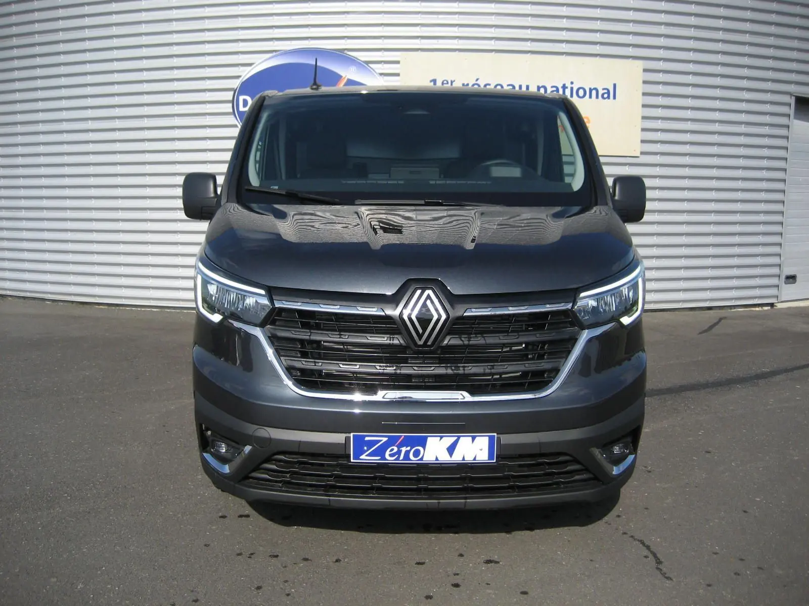 Vue frontale d'un Renault Trafic Fourgon L1H1 Advance gris comète avec calandre noire et phares LED allumés.